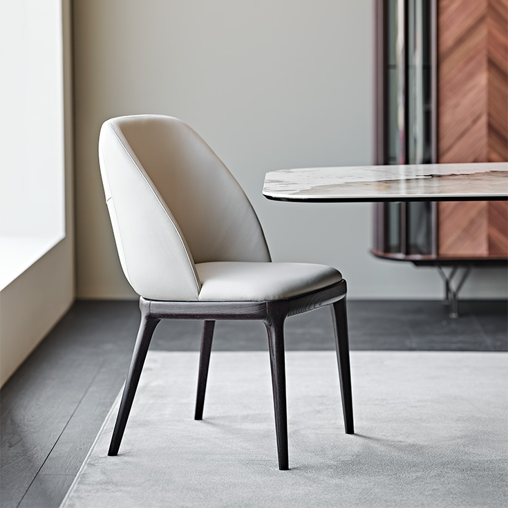 MARIEL Chaise design avec dossier enveloppant et structure en bois massif, revêtement en tissu ou cuir. Disponible chez D-Style Interior.