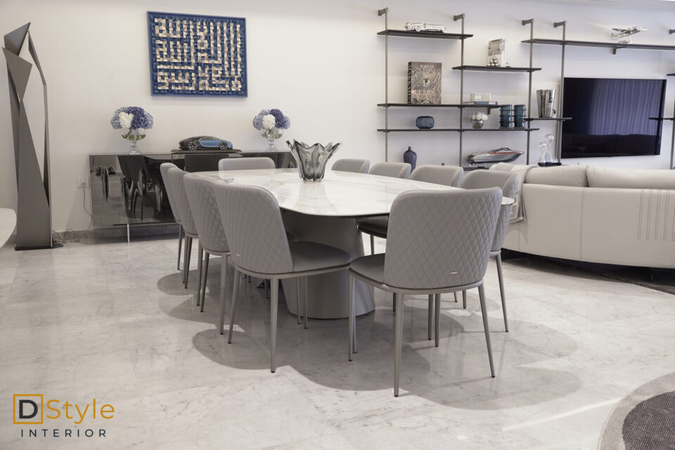 Table de salle à manger à plateau de marbre sur piètement conique, chaises grises matelassées, dans un séjour contemporain aménagé par D-Style