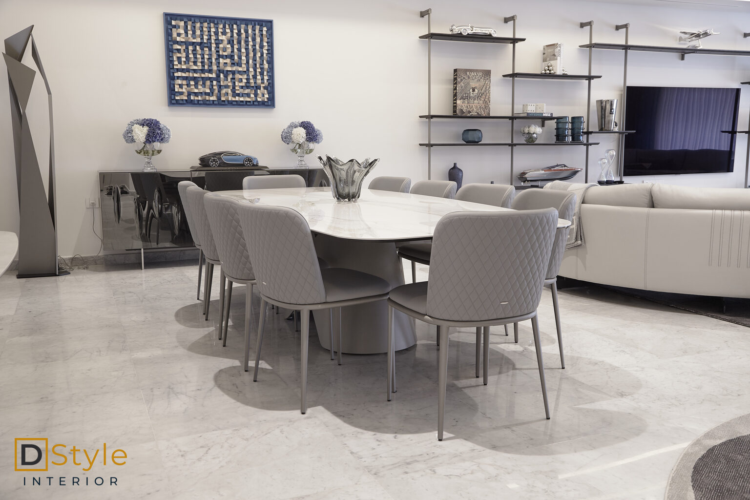 Table de salle à manger à plateau de marbre sur piètement conique, chaises grises matelassées, dans un séjour contemporain aménagé par D-Style
